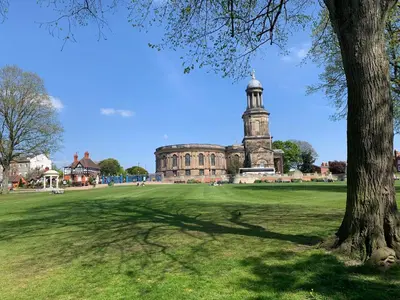 an old building with a clock tower in a field at Abbots Mead Hotel in Shrewsbury