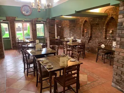 a restaurant with wooden tables and chairs and a brick wall at Abbots Mead Hotel in Shrewsbury