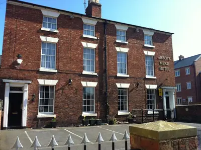 a red brick building with a fence in front of it at Abbots Mead Hotel in Shrewsbury