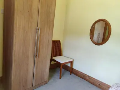 a room with a wooden cabinet and a mirror at Bryn Cottage in Llandderfel