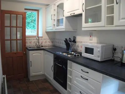 a kitchen with white cabinets and a microwave at Bryn Cottage in Llandderfel