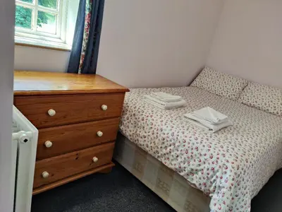a small bedroom with a bed and a dresser at Bryn Cottage in Llandderfel