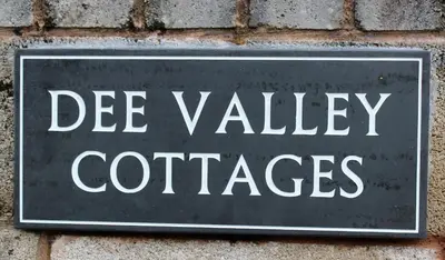a sign on a brick wall with the words devalley containers at Dee Valley Cottages in Llangollen