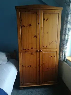 a wooden cabinet in a bedroom next to a bed at Ty Newydd in Llangadog