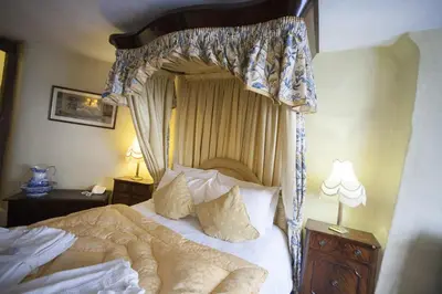 a bedroom with a canopy bed with white sheets and pillows at The Lion Hotel Shrewsbury in Shrewsbury