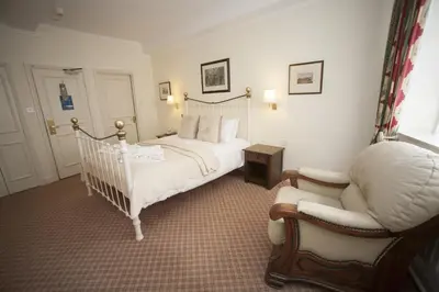 a bedroom with a white bed and a chair at The Lion Hotel Shrewsbury in Shrewsbury