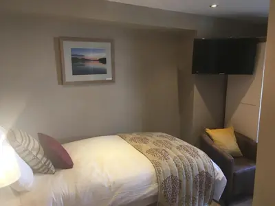 a small bedroom with a bed and a chair at Plas Yn Dre in Bala
