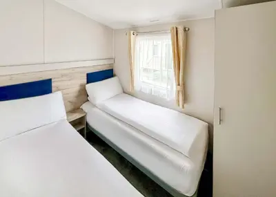 a small room with two beds and a window at Pencnwc Holiday Park in Llanllwchaiarn