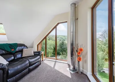 a living room with a leather couch and large windows at Slate House Lodges in Towyn
