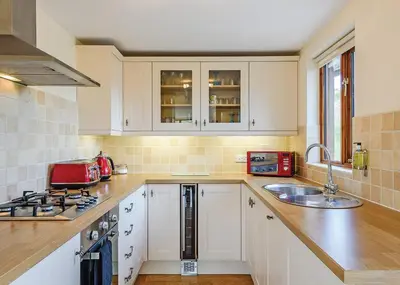 a kitchen with white cabinets and a sink at Slate House Lodges in Towyn