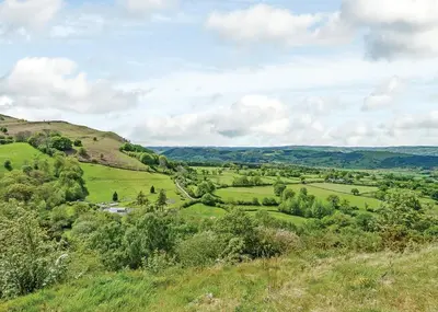 a view of a green field from a hill at Slate House Lodges in Towyn
