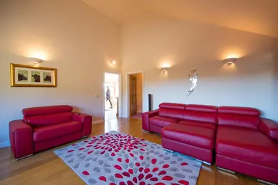 a living room with a red couch and a rug at Y Grange in Llanfihangel-y-creuddyn