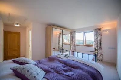 a bedroom with a large bed with purple sheets and a window at Y Grange in Llanfihangel-y-creuddyn
