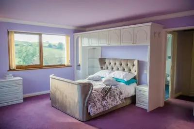 a bedroom with a canopy bed with purple walls at Y Grange in Llanfihangel-y-creuddyn