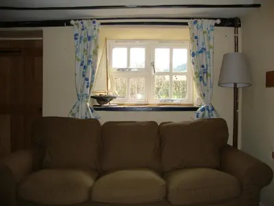 a couch in a living room with a window at Ceiros Cottage in Llangammarch Wells