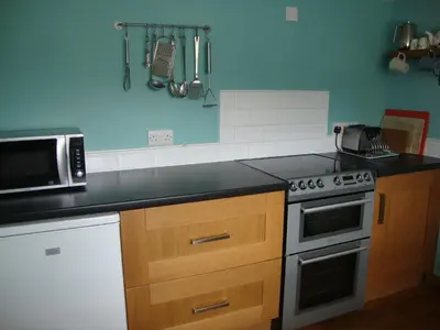 a kitchen with a stove and a microwave at Ceiros Cottage in Llangammarch Wells
