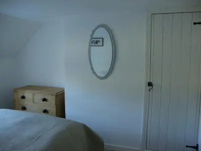 a bedroom with a mirror and a bed and a dresser at Ceiros Cottage in Llangammarch Wells