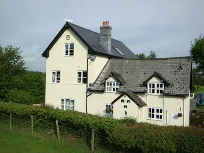 a white house with a black roof at Ceiros Cottage in Llangammarch Wells