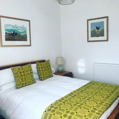 a bedroom with a white bed with a yellow blanket at Llety Brynawel Guest House in Pennal