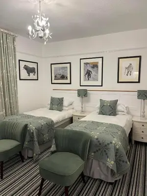 a bedroom with two beds and a chandelier at Llety Brynawel Guest House in Pennal