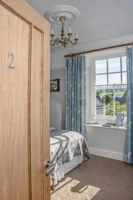 a bedroom with a bed and a window and a chandelier at Llety Brynawel Guest House in Pennal