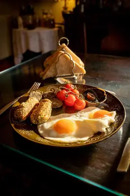 a plate of eggs and other food on a table at Taldraeth - Old Vicarage Guest House in Penrhyndeudreath