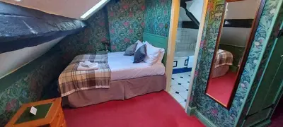 a small bedroom with a bed and a mirror at Bron-Y-Graig in Corwen