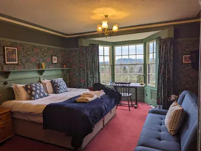 a bedroom with a bed and a chair and a window at Bron-Y-Graig in Corwen