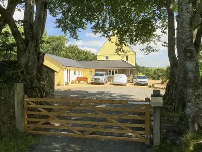 a yellow house with cars parked in front of it at Brynllin Holiday Cottages - Dildre in Penuwch