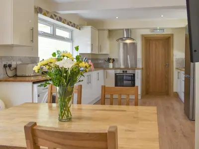 a vase of flowers on a wooden table in a kitchen at Brynllin Holiday Cottages - Dildre in Penuwch