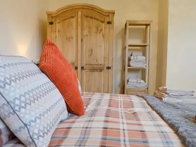a bedroom with a bed with orange and blue pillows at Y Bwthyn Pren in Aberaeron