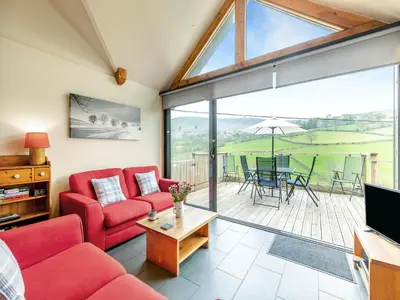 a living room with red furniture and a large window at Wern Ddu Cottage in Pen-y-bont-fawr
