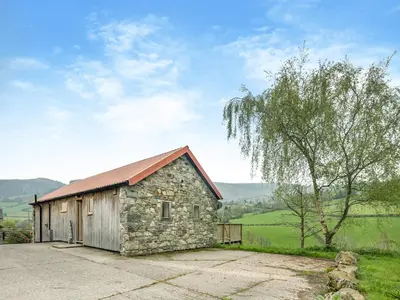 a stone building with a tree in the background at Wern Ddu Cottage in Pen-y-bont-fawr