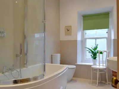 a bathroom with a tub and a toilet and a window at Tyllwyd Farmhouse in Capel Bangor