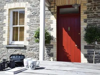 a red door of a house with two cups on the doorstep at Tyllwyd Farmhouse in Capel Bangor