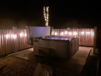 a hot tub in a backyard at night at Tyllwyd Farmhouse in Capel Bangor