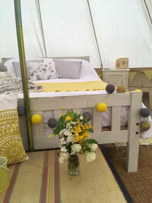 a bed in a tent with a vase of flowers at Cefn Crib Glamping in Machynlleth