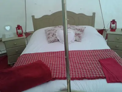 a bed with a red and white blanket and pillows at Cefn Crib Glamping in Machynlleth