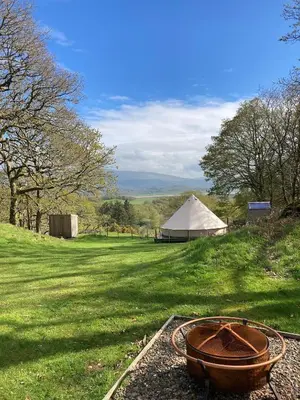 a field with a tent and a bowl on the grass at Cefn Crib Glamping in Machynlleth