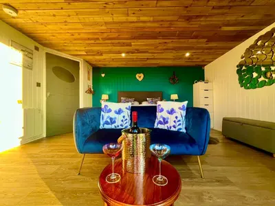 a living room with two blue chairs and a table with wine glasses at The Pod & Cwtch luxury accommodation in Aberaeron