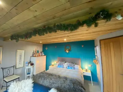 a bedroom with a bed and a blue wall at The Pod & Cwtch luxury accommodation in Aberaeron