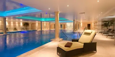 a swimming pool with a couch and a chair in a building at Lion Quays Resort in Oswestry
