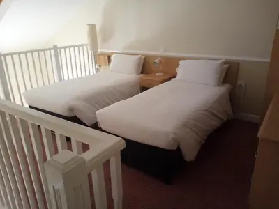 two beds with white sheets in a room at Moreton Park Hotel in Chirk