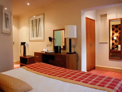 a bedroom with a bed and a desk and a mirror at Metropole Hotel and Spa in Llandrindod Wells