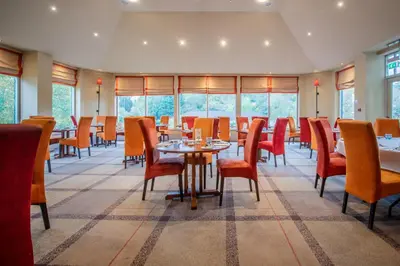 a dining room with tables and chairs and windows at Metropole Hotel and Spa in Llandrindod Wells
