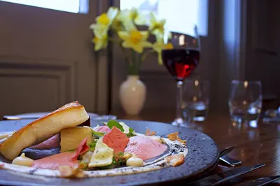 a plate of food on a table with a glass of wine at The Falcondale Country House Hotel in Lampeter
