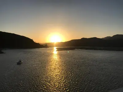 a sunset on a river with a boat in the water at The Sandpiper in Barmouth