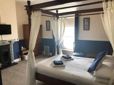 a bedroom with a canopy bed with a fireplace at Leamington House in Barmouth