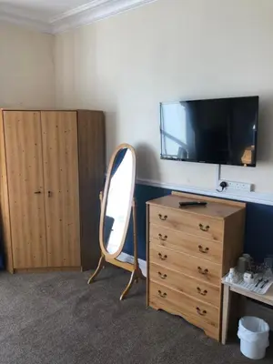 a room with a mirror on a dresser and a tv at Leamington House in Barmouth