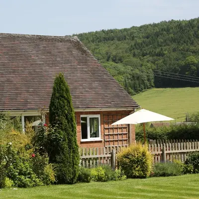 a house with a fence and an umbrella in the yard at Pheasant Walk at Eaton Manor in Church Stretton
